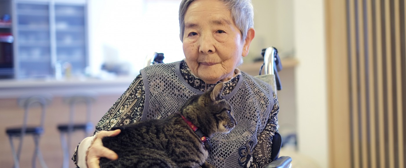 Older woman sits in wheelchair with cat on her lap